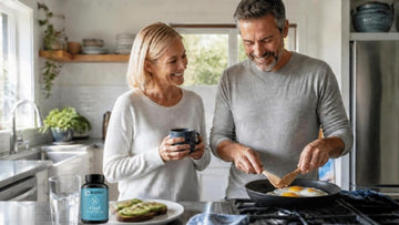 Couple in their 50s cooking breakfast together, with a bottle of BoostCeuticals CoQ10 on the kitchen bench